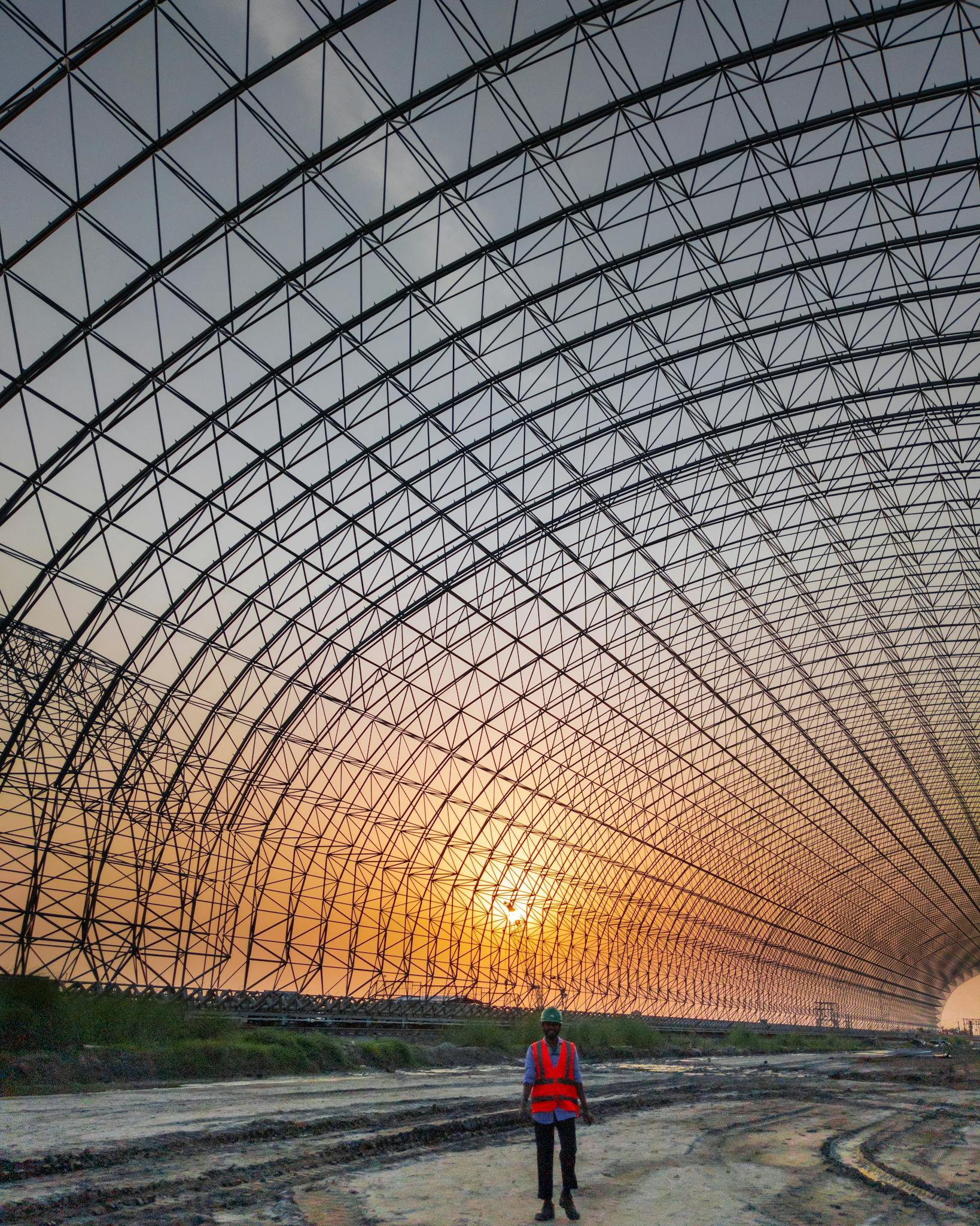 Engineer standing inside a large metal frame structure at sunset, Bangladesh.